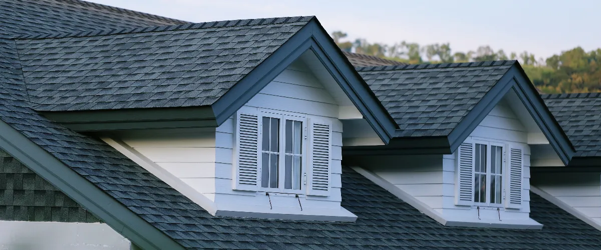 a residential roof featuring dormer windows and dimensional asphalt shingles
