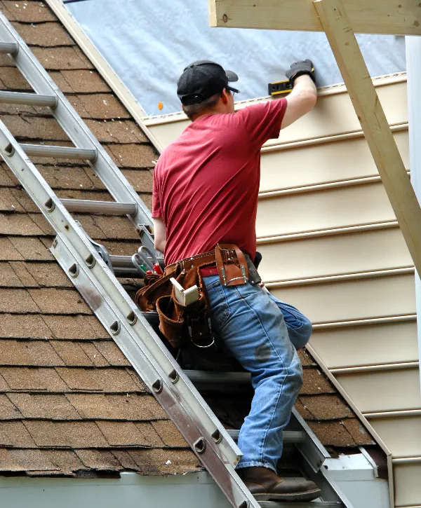 a worker installing siding on the exterior wall of a building