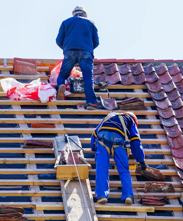 two construction workers actively engaged in a roof replacement project