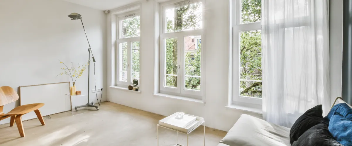 A living room with large tall windows, allowing natural light to fill the space