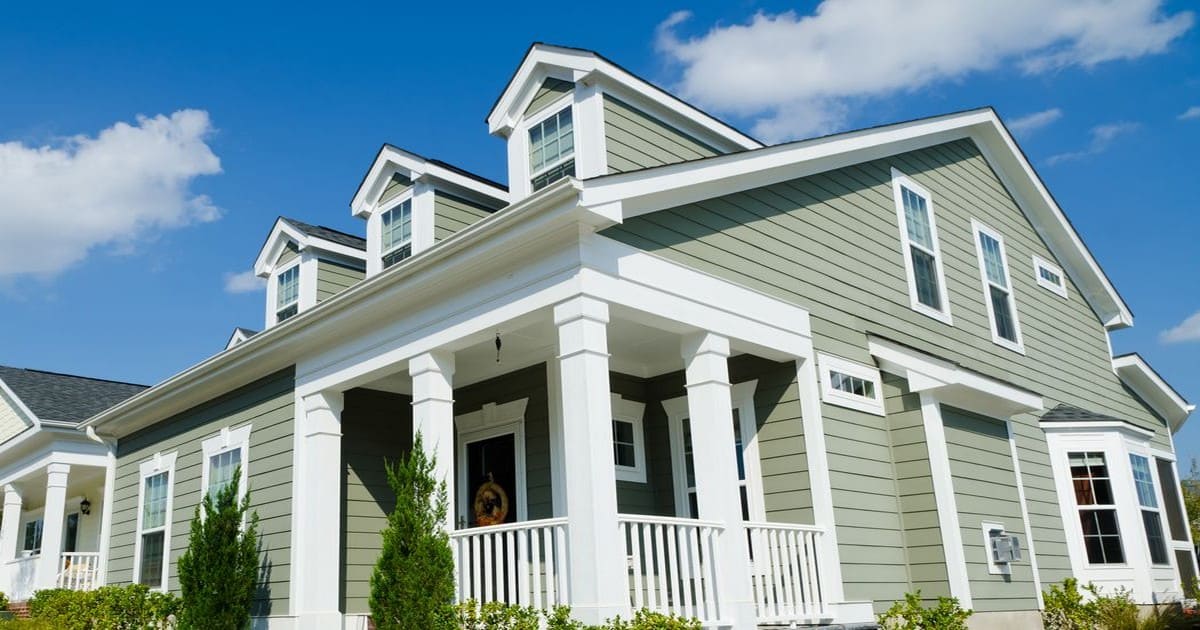 A beautiful suburban home with a completed siding installation in Colts Neck, NJ, showing sage green siding and a white front porch.