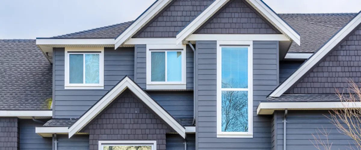 the exterior of a modern house with white framed windows, likely made of low-maintenance materials such as vinyl or fiberglass