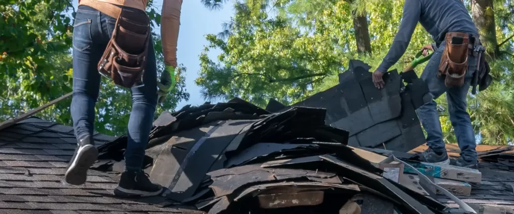 Roofing contractors removing old materials to prepare for an insurance-backed roof replacement.