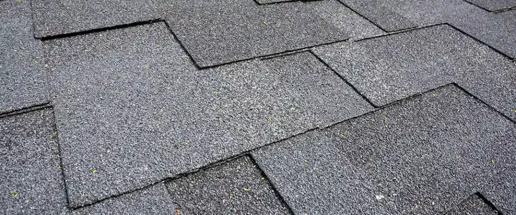 Close-up perspective of high-quality gray asphalt shingles with weather-resistant granules installed on a residential roof.