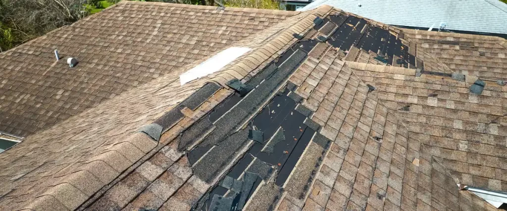 Aerial view of a roof showing advanced weathering with large patches of missing granules and shingles.