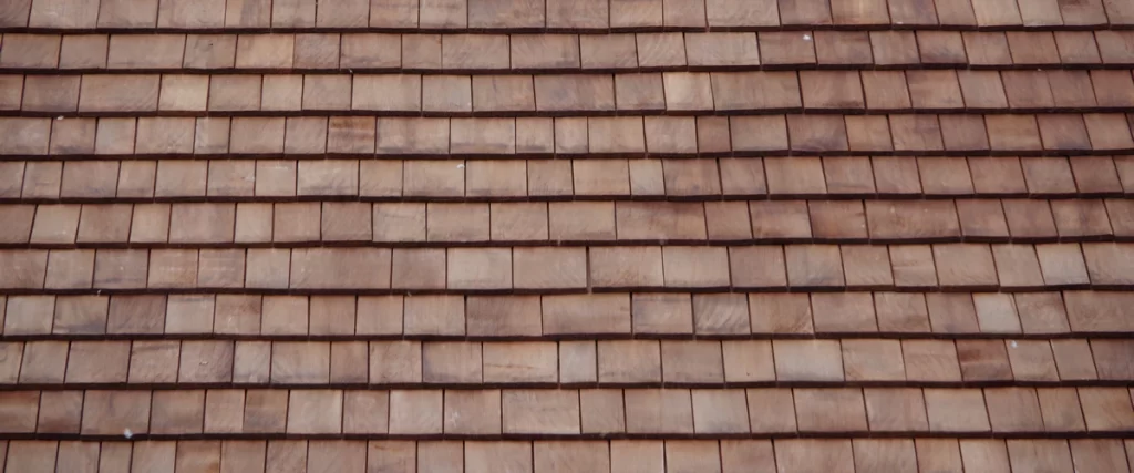 Evenly spaced natural cedar wood shingles showing the warm brown grain and traditional rustic aesthetic of a timber roof.