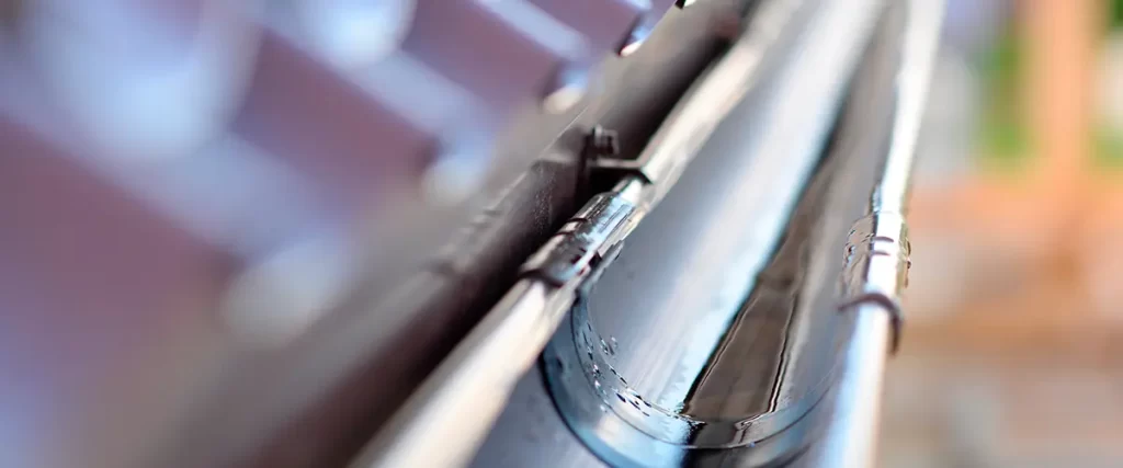 Close-up of seamless aluminum rain gutter installation on a residential roof for efficient water drainage