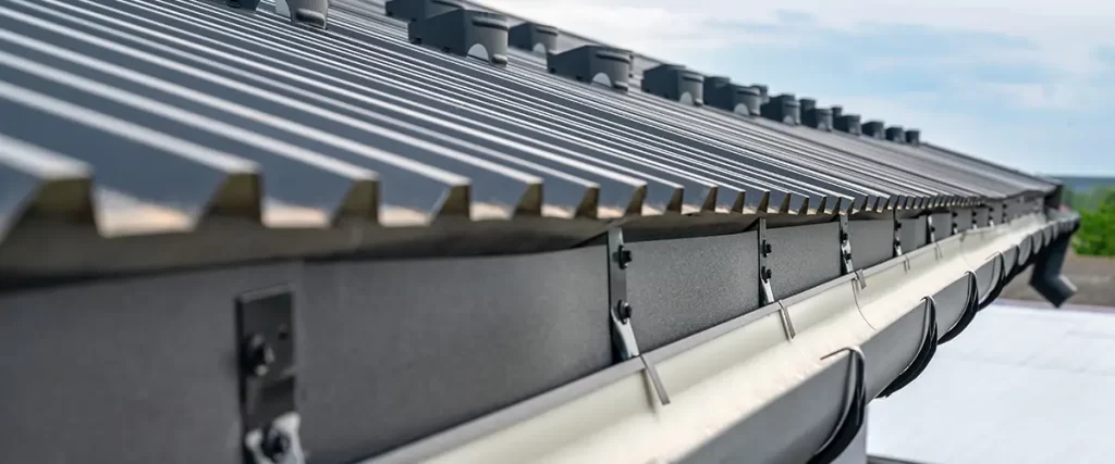 Close-up of seamless metal gutters installed on a corrugated metal roof drainage system