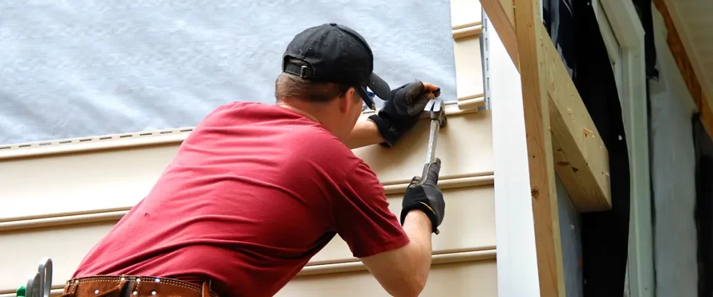 Contractor installing vinyl siding panels on a home exterior during professional siding replacement project