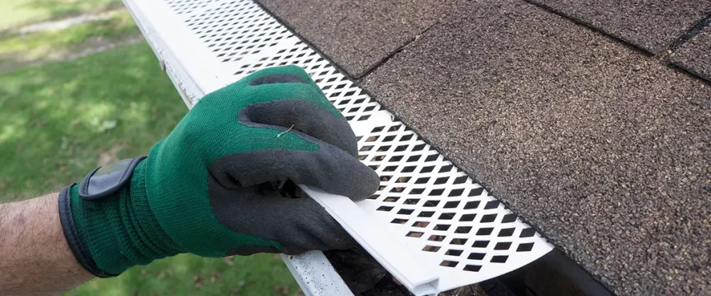 Installing gutter guards on residential rain gutters to prevent leaves, debris, and clogs