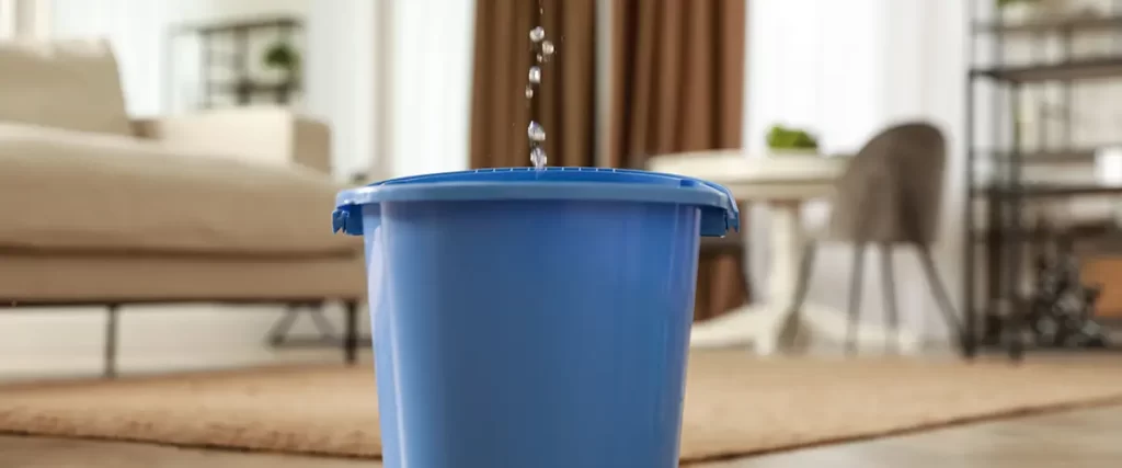 Water leaking from ceiling into a bucket during residential water damage restoration